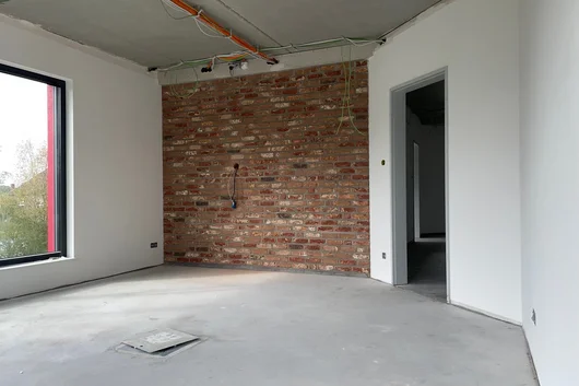 Büroraum bei K60 in Langenberg während des Innenausbaus mit Sichtziegelwand und offenen Deckeninstallationen