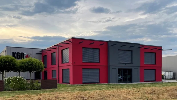 Außenansicht des zweigeschossigen K60-Bürogebäudes in Langenberg mit roter Fassade und grauem Eingangsbereich